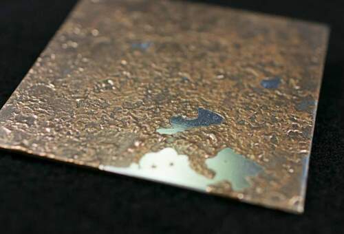 Orange bronze broken open on polished aluminium
